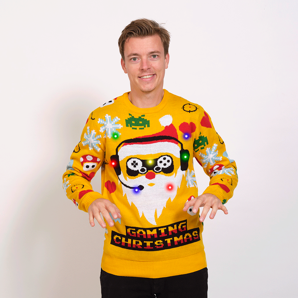 Un uomo posa indossando un maglione natalizio giallo a tema gamer.
